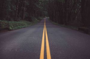 Photo of an asphalt road winding through trees.